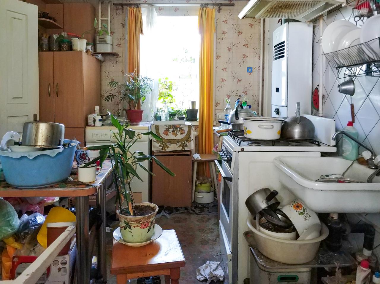 Une vieille cuisine complètement encombrée avec de la vaisselle sale partout.