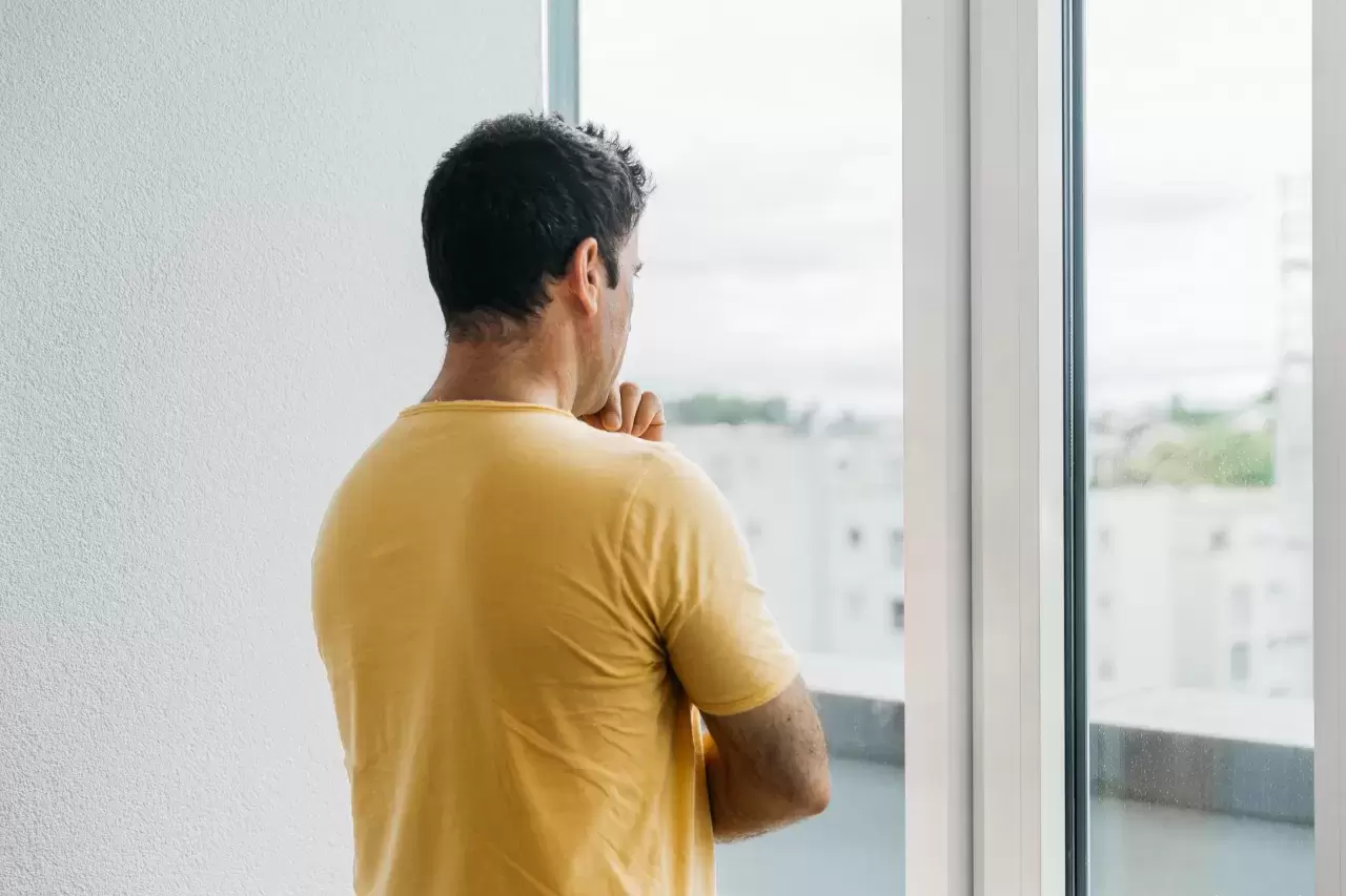 Mann mit Migrationshintergrund schaut aus dem Fenster
