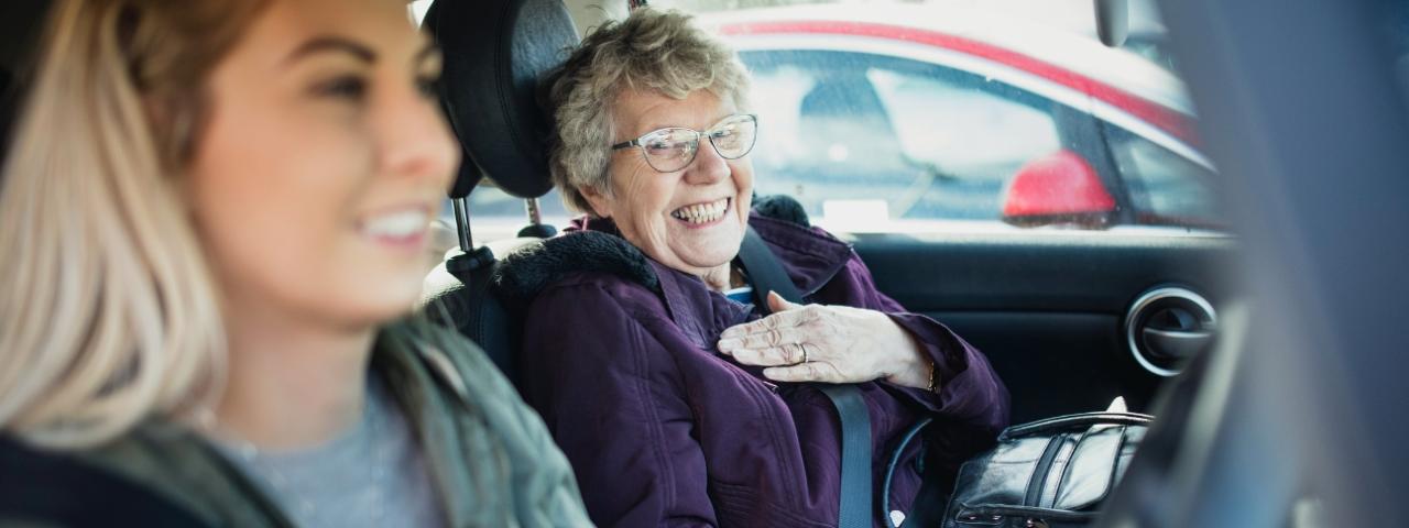 Eine ältere und eine jüngere Frau sitzen lachend im Auto