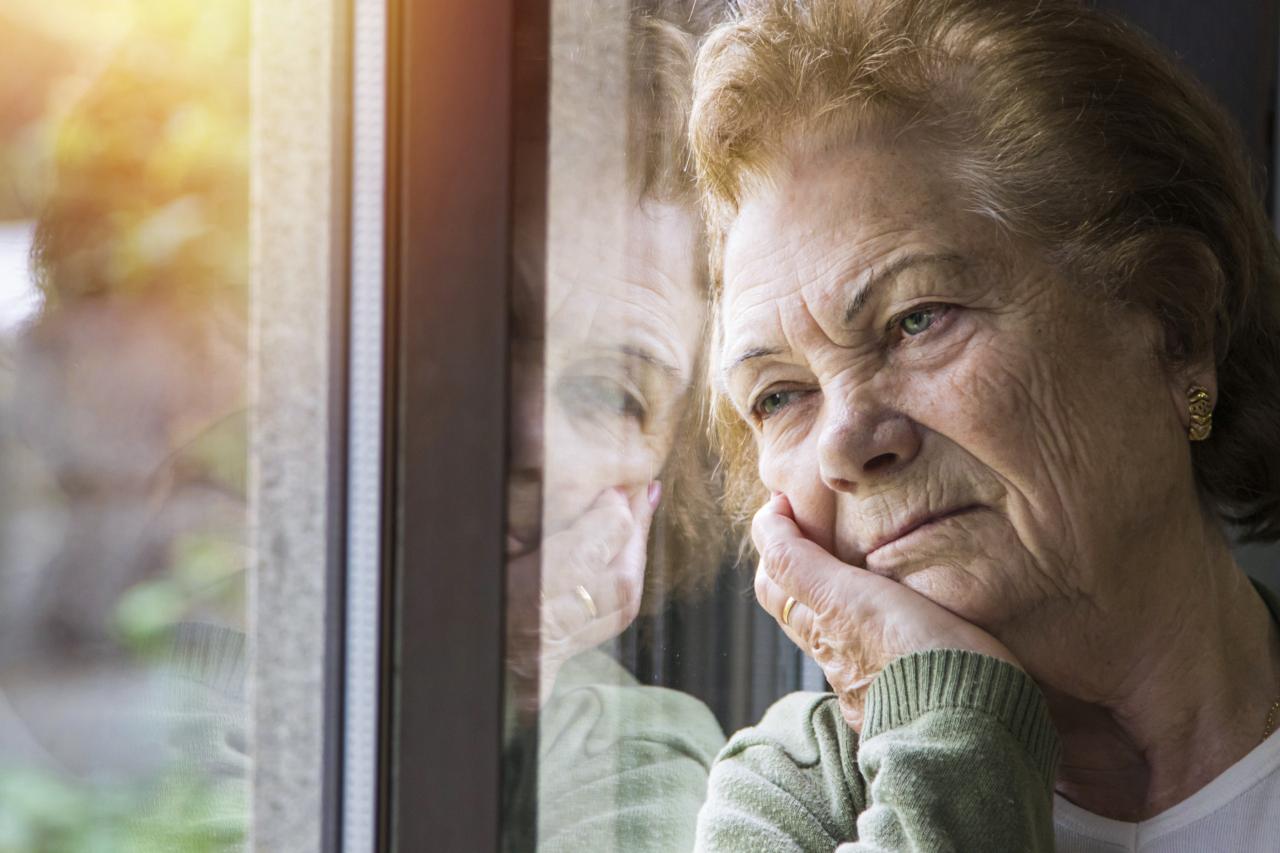 Einsame Frau im Alter schaut traurig aus dem Fenster