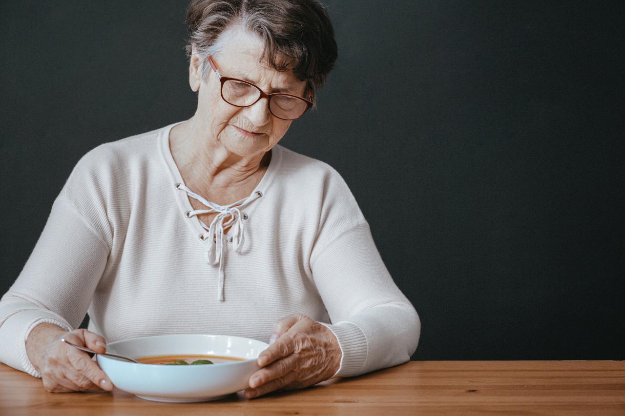 Femme sans appétit assise devant son assiette à soupe.