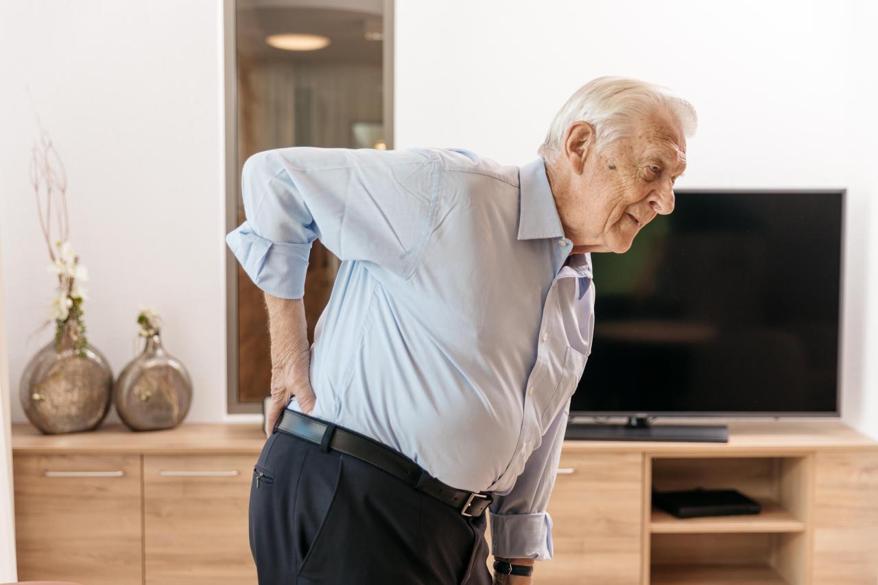 Un vieil homme se tient courbé en raison de douleurs dorsales.