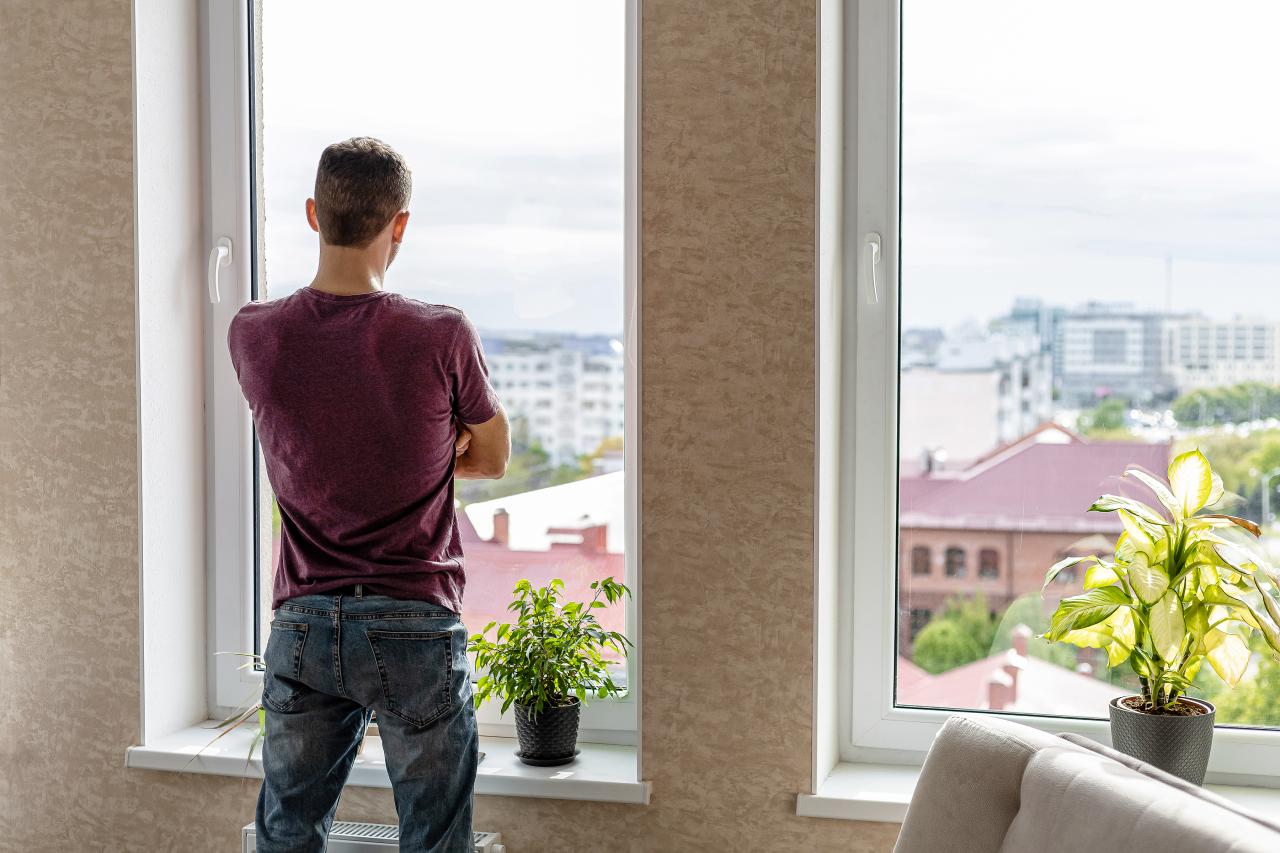 Mann steht am Fenster und blickt hinaus