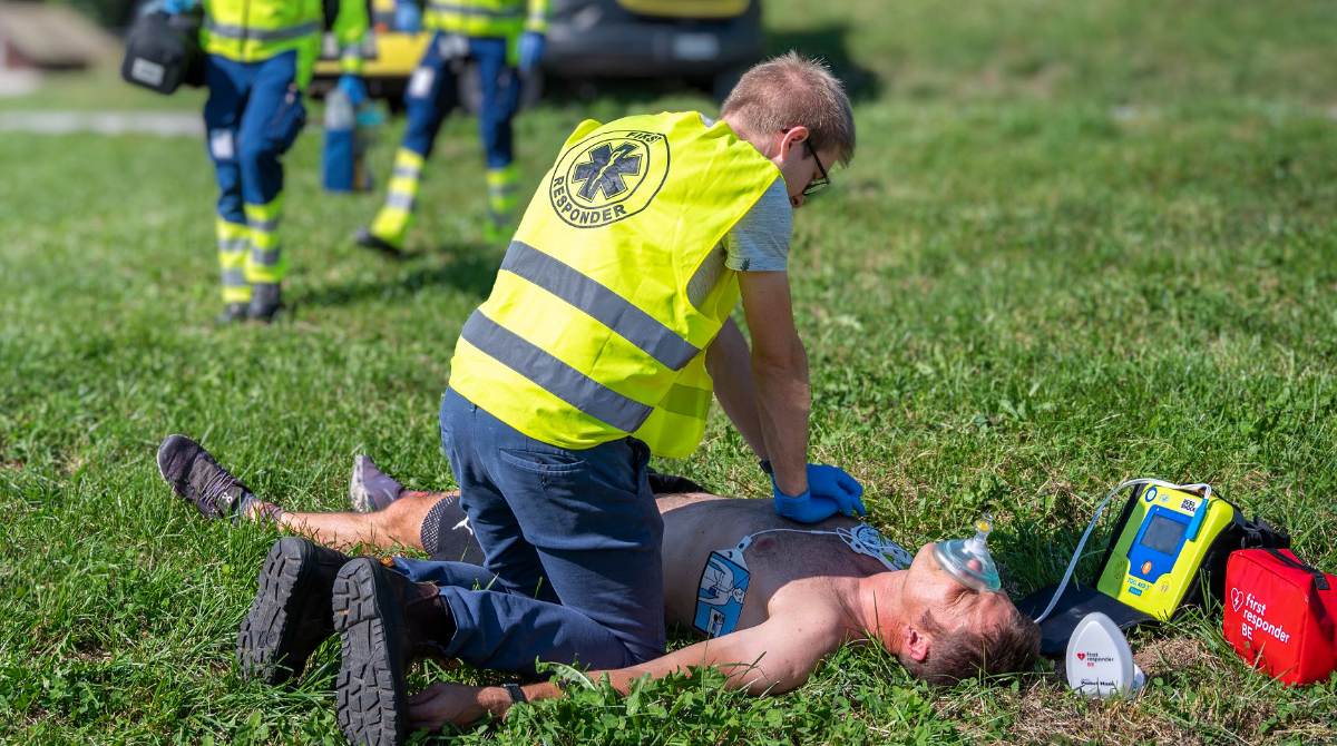 Ein First Responder mit gelber Weste führt eine Reanimierung durch