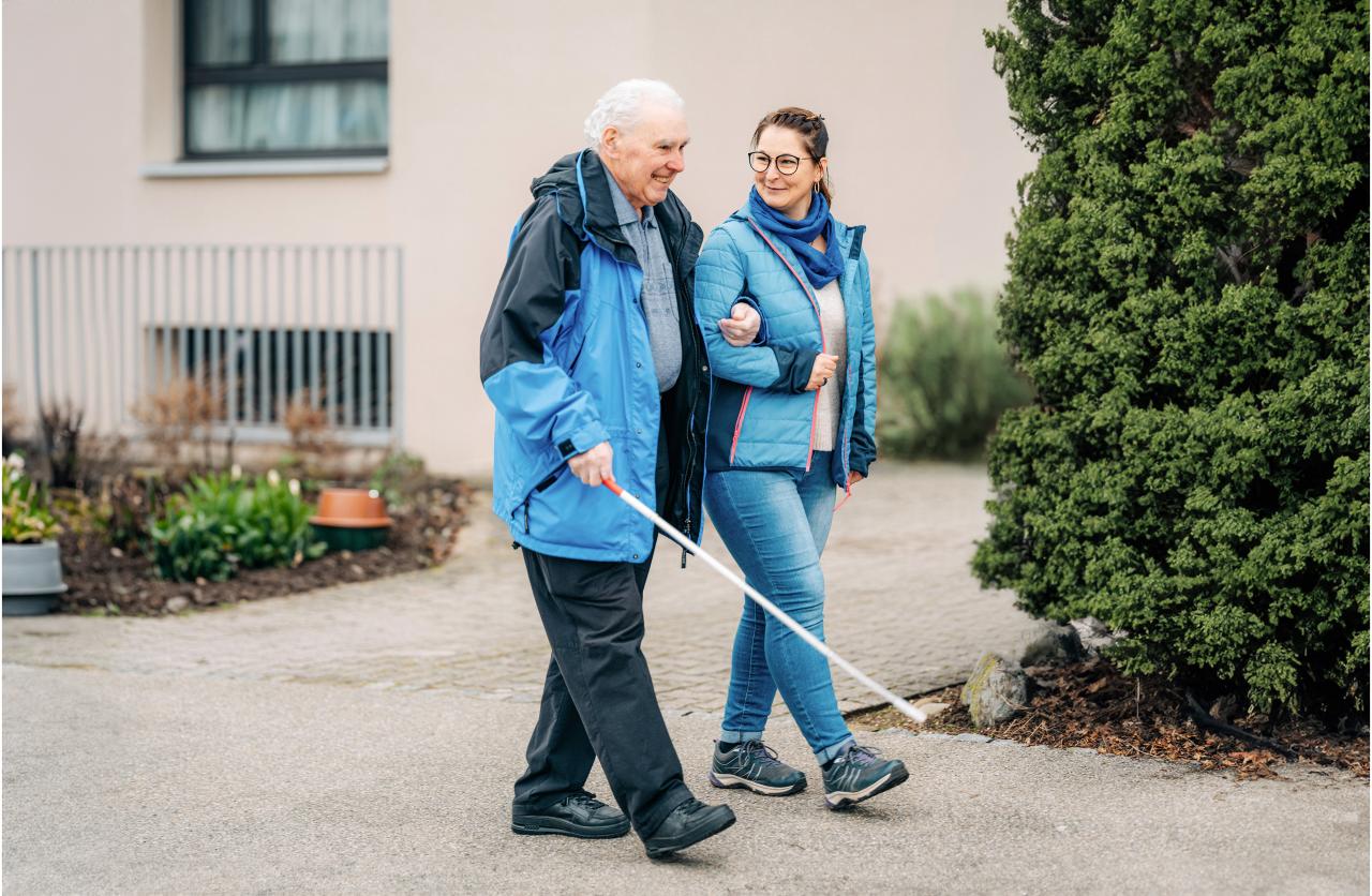 Hans und Anita spazieren, Hans geht am Stock und ist bei Anita eingehakt