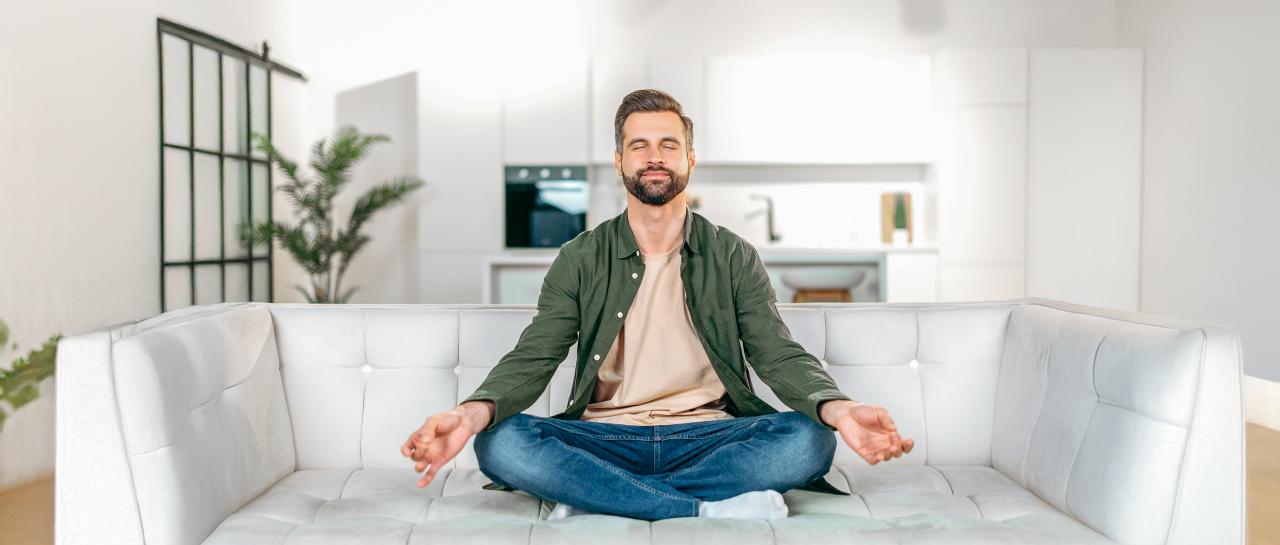 Ein Mann sitzt auf einem Sofa und meditiert