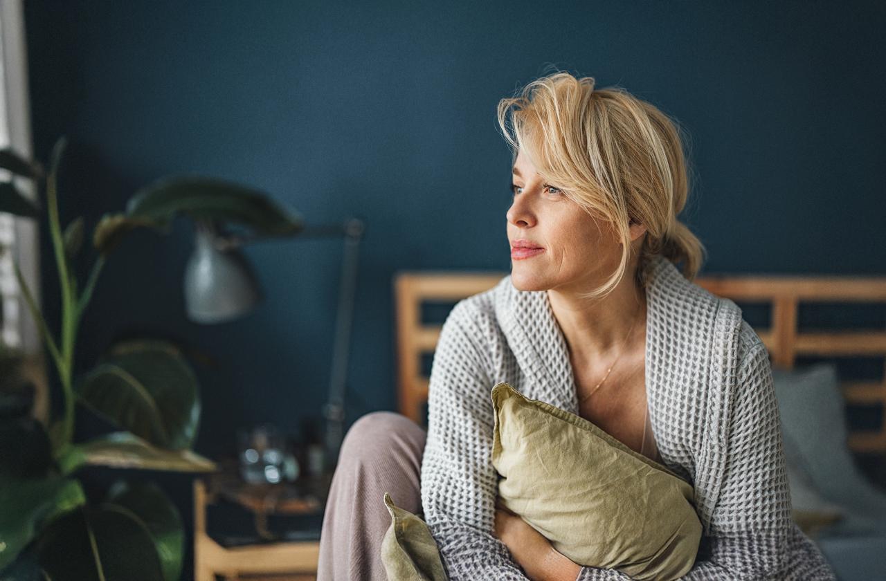 Eine Frau ist gerade erwacht und hat sich im Bett aufgerichtet