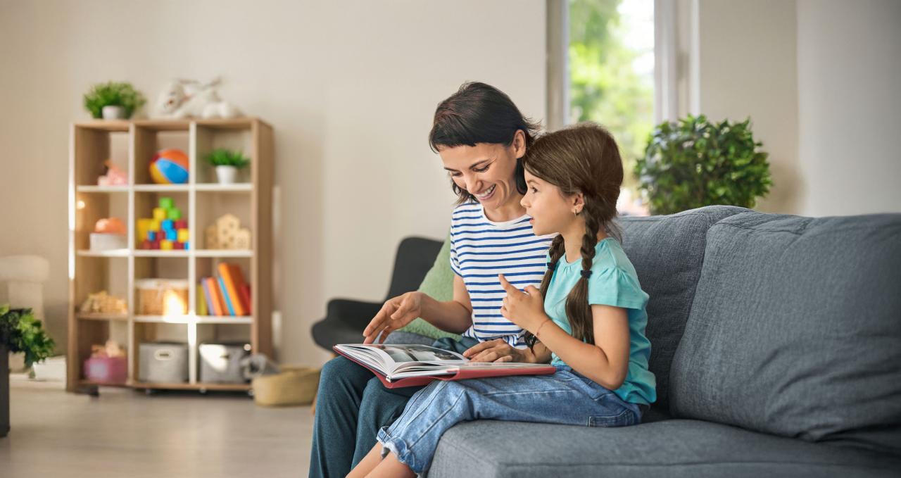 Frau und Mädchen schauen zusammen ein Bilderbuch an