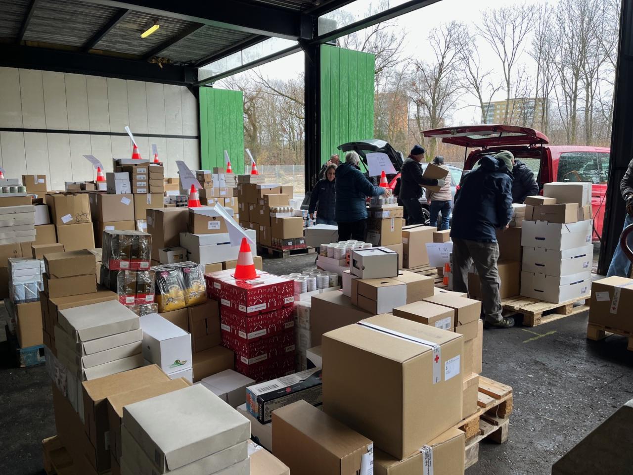 Menschen mit Autos holen Warenspenden in einem Lager ab.