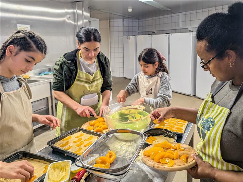 Frauen unterschiedlichen Alters backen zusammen Pfirsichkuchen.
