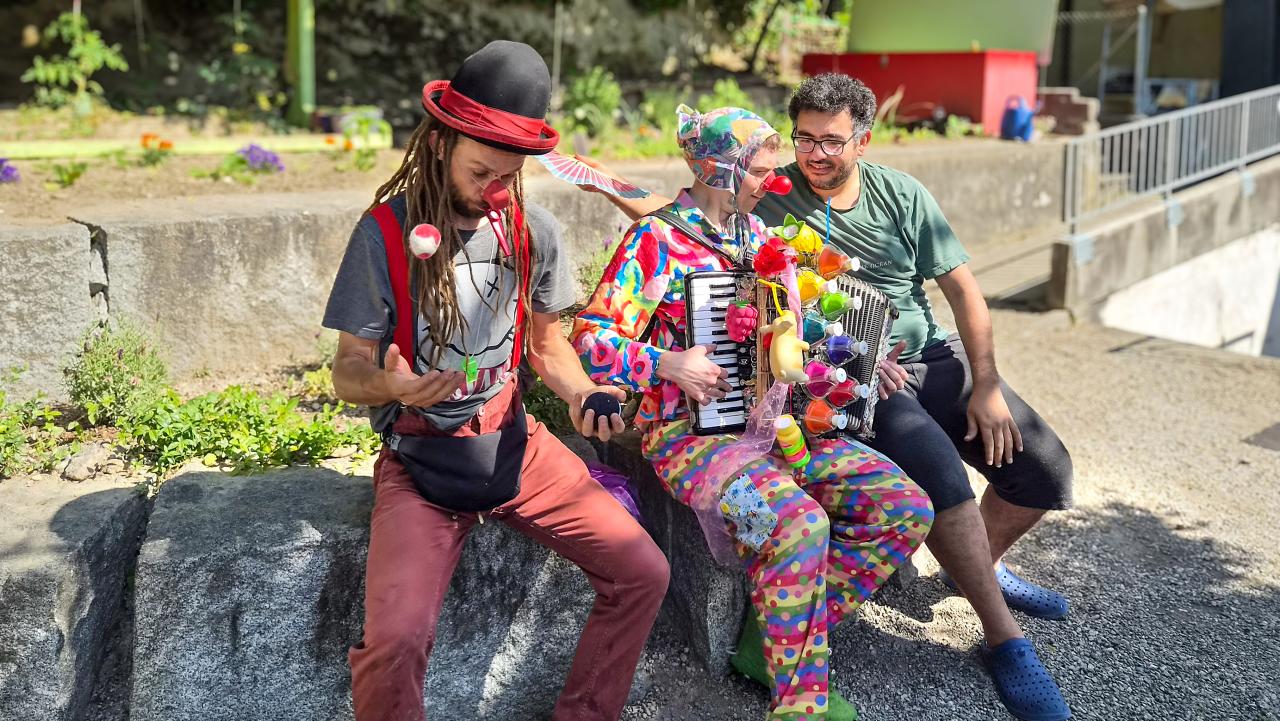 Zwei Clowns musizieren mit einem geflüchteten Mann.