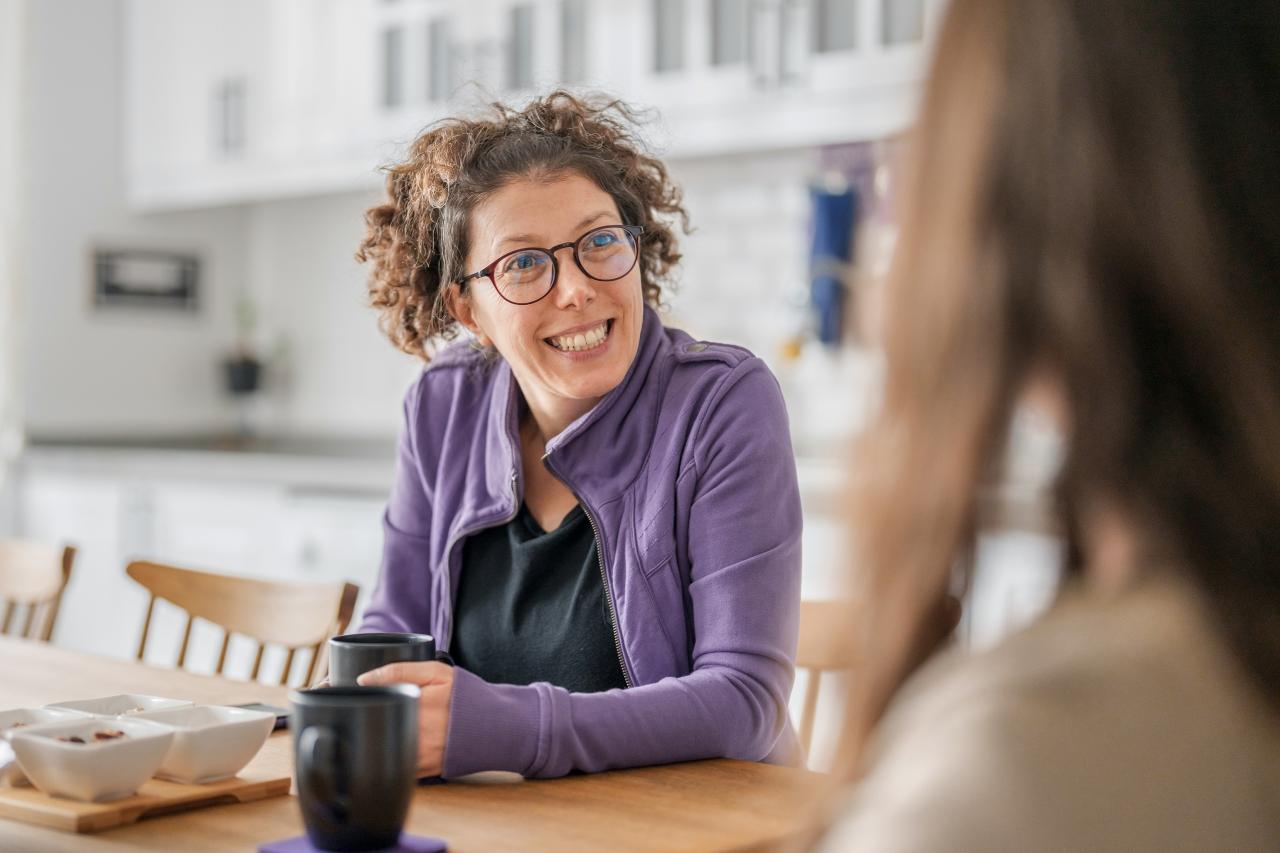 Zwei Frauen sitzen sich bei einem Gespräch am Tisch gegenüber.