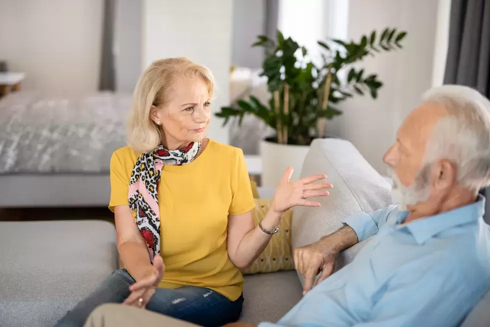 Ältere Frau und älterer Mann unterhalten sich auf dem Sofa