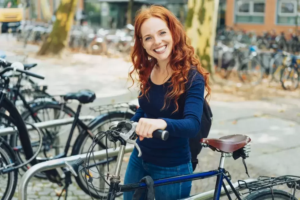 Ein junge, lachende Frau stellt ihr Fahrrad ab.
