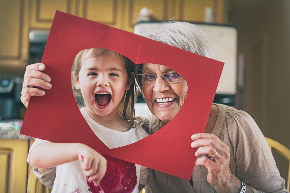 Ein Enkelkind und eine Grossmutter gucken lachend in die Kamera.