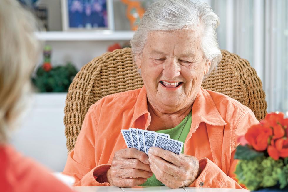 Zufriedene Seniorin beim Kartenspielen