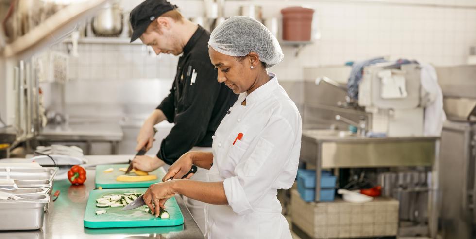 Ein Freiwilliger kocht mit einer Geflüchteten