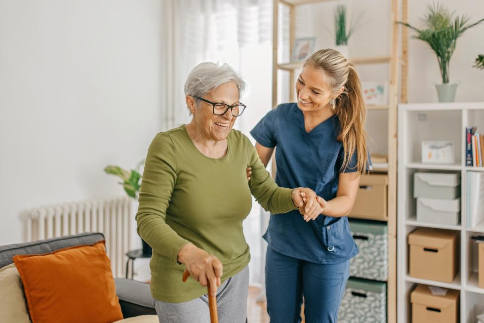Pflegefachfrau stützt ältere Frau beim Gehen