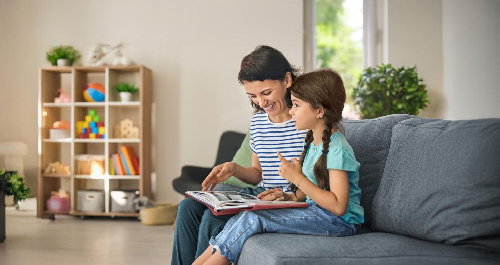 Frau und Mädchen schauen zusammen ein Bilderbuch an