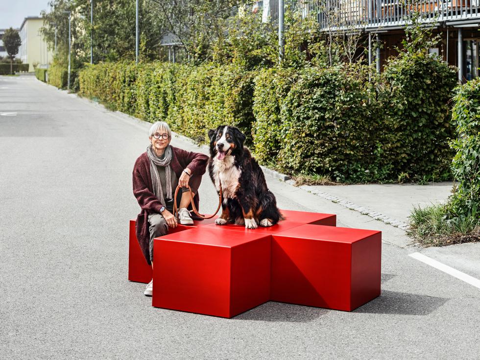 Moderne Seniorin sitzt mit Berner Sennenhund auf einer Bank